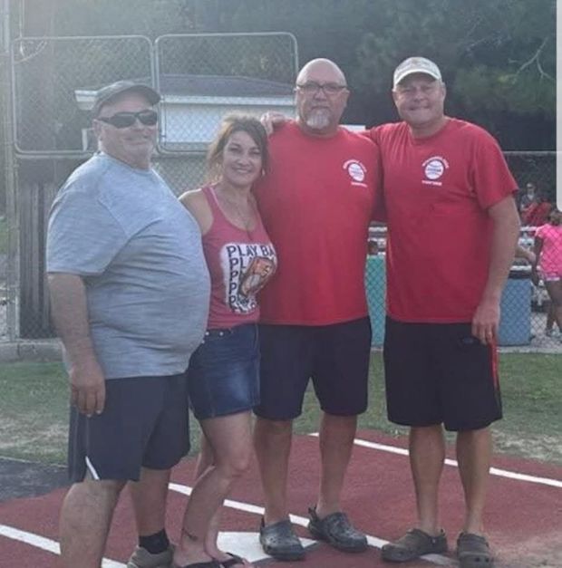 Four adults in red shirts standing together on the field