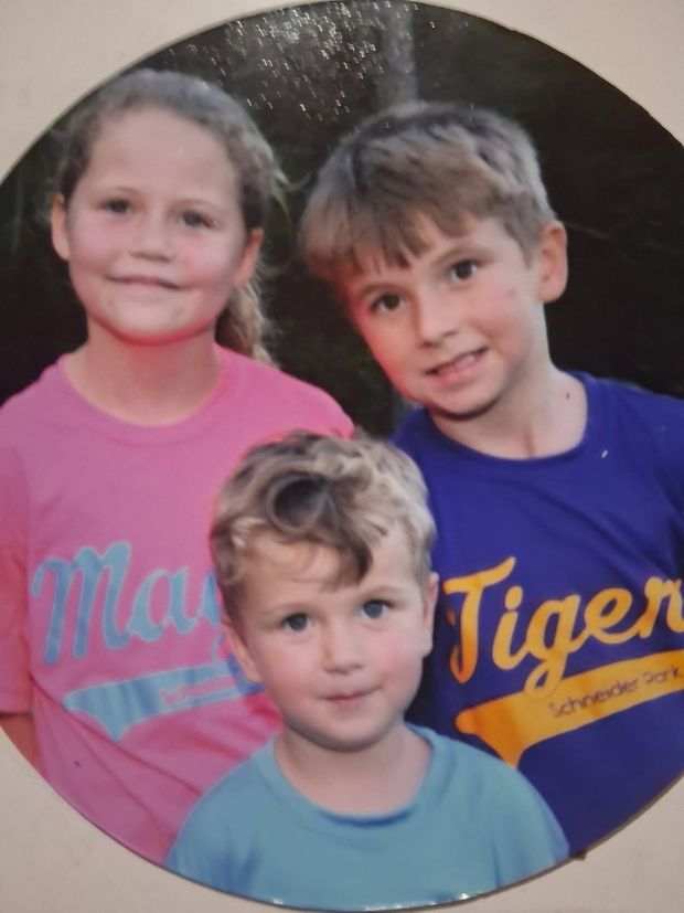 A round printed photograph of three children in team shirts