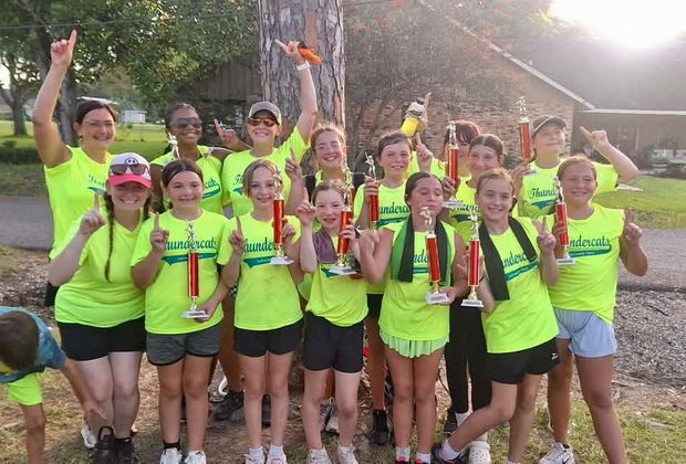 A team in neon yellow Thundercats shirts holding red trophies at night