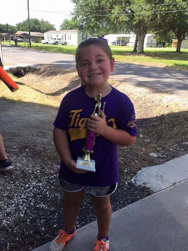 A young girl in a purple Tigers shirt holding a purple trophy