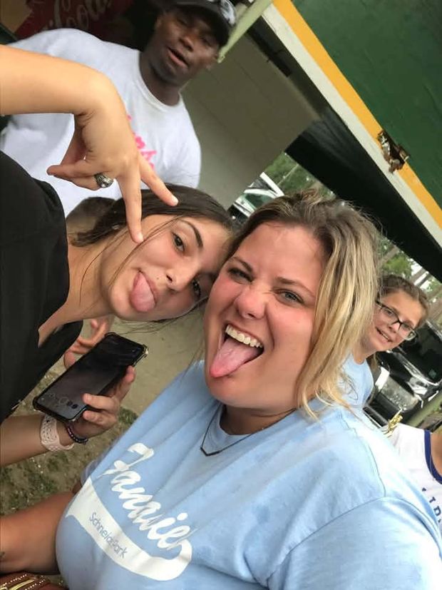 A woman and girls making silly faces in a close selfie under the pavilion