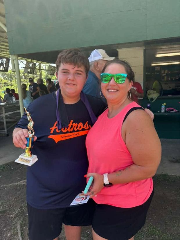 A young player holding a trophy standing beside a smiling woman