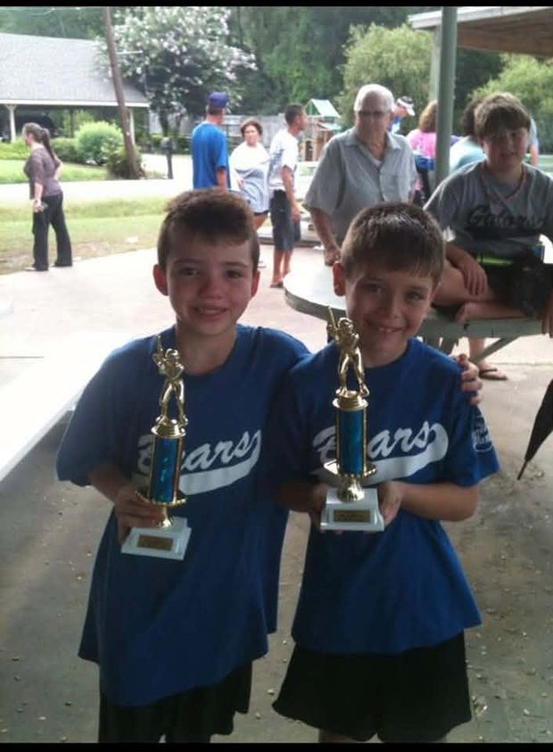 Two boys in blue Bears shirts each holding a trophy