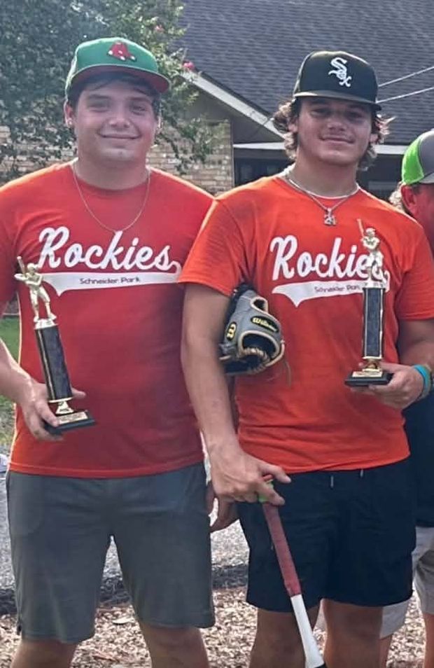 Two teenage players in Rockies shirts holding trophies and gloves