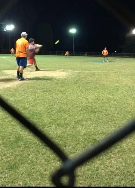 Players on the field under bright lights at night seen through the fence
