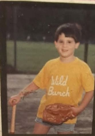 An old print of a young player in a yellow Wild Bunch shirt holding a bat, with a glove under one arm
