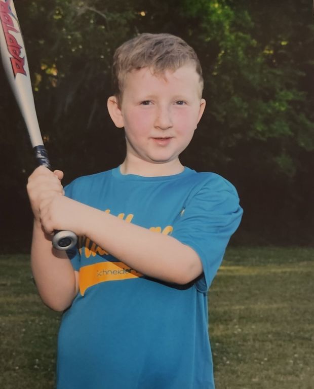A printed portrait of a boy in a teal Wildcats shirt holding a bat